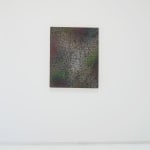 A multicolored abstract painting on canvas hanging on a white wall.
