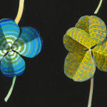 Detail of two clovers. One is blue with concentric details and one has intricate yellow designs.