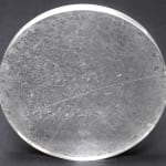 A clear disk with etchings on a dark grey background.