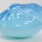 A cushion-like blown-glass sculpture, top two-thirds translucent blue, bottom one-third opaque blue.