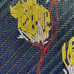 Heavily layered and textured paint on canvas creates a woven pattern of four yellow and white flower buds with thin red stems against a navy background The pattern is inspired by a dress worn by Michelle Obama in twenty sixteen