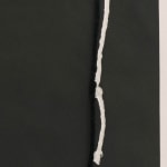 Detail of black square with black string that went through press but has been moved, showing white outline of string.