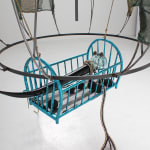 A detailed image of a teardrop shaped steel sculpture.with baby crib.