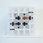 5x5 grid of clear, square windows with white borders in a plexiglass box. Each window shows different cutouts and flaps.