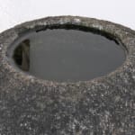 Detail of dark stone, round basin full of water.