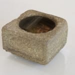 Weathered square stone basin with circle in center holding water.