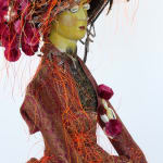 An angle shot of the victorian doll in her dress and hat.