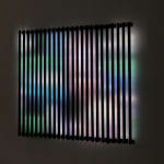 Still image of rectangular piece with multiple flat bars of multi-colored LEDs that displays many blurred scenes taken from old family home movies onto the wall behind it