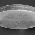 Top view of a clear disk with etchings on a dark grey background.