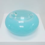 A light blue UFO-shaped sculpture with two clear bubbles on top, top view on pedestal.