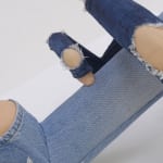 Detail of expose skin under denim rips with bent "knees."