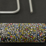 Detail; front view of a variety of white, blue, red, and yellow 1D cutouts attached to black roller head, with metal handle.
