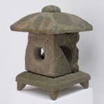 Weathered stone lantern with square base and feet, square body with hole in the center, and domed topper.