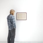 A white man admires If Word Wallower Best as it hangs on a white wall