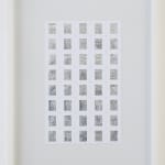 Framed; front view of a 5x8 grid of rectangular foil slides, each with unique raised linear designs, in white mounts.