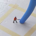 Close up of the tiny figurine painting the chair leg in Untitled (man painting chair II)