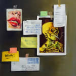 Blurred items taped to brown wall, including: pictures of a skeleton smoking a cigarette and a woman’s mouth and nose, postcards, an envelope and other pieces of paper.