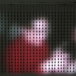 Still image of Home Movies Pause (David) with LEDs shining onto the wall to create a blurred image of a person in a red shirt