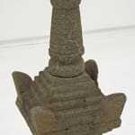 Cylindrical top on pyramid shaped topper of stone sculpture.