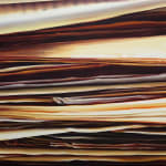 Stack of tan and gray papers viewed up close from the side.