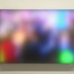 Still image of rectangular piece with multiple multi-colored LEDs behind Plexiglass that displays a blurred scene of protesters from the Women’s March in twenty seventeen