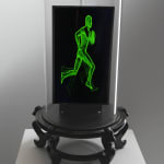 Sculpture with monitor displaying green running man.