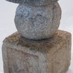 Square base and rounded body of stone sculpture.