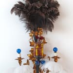 An image of a sculpture piece with feathers, beads, marbles.