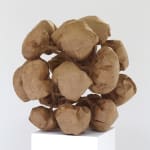 Craft paper sculpture depicts multiple finger print textured ballooned puffs which create a loose image of a pinecone The puffs are connected to each other by various stems which trace back to a central humanoid figure hidden at the center