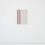 A green, pink, and white abstract painting mimicking fabric hangs on a white wall.