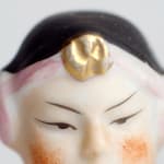 still from video shows top half of a painted figurine's face on white background