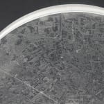 Detail; a clear disk with etchings on a dark grey background.