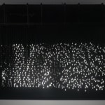 An image of piece with scattered string lights showing people walking.