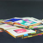 Four colorful books with Post-it notes stacked on each other. The books are opened to pages depicting blurred images of flowers.