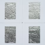 Detail; 2x2 grid of rectangular foil slides, each with unique raised linear designs, in white mounts.