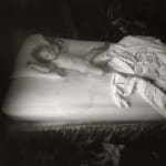Virginia sleeping with wet bed stains and dolls on floor, from the Immediate Family series by Sally Mann