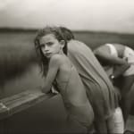 young girl in bathing suit leaning over lake fence, hair blowing in wind, by Sally Mann from the Immediate Family series
