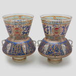 Pair of Mamluk-revival enameled clear glass Mosque lamps, circa 1900 clear glass Mosque lamps applied with six curved loops under a high conical neck, decorated with rows of gilt enameled Kufic inscriptions against blue background 42.5 x 33 x 33 cm