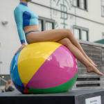 Swimmer sitting on beach ball near businesses at The Seaport in New York City