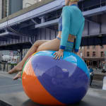Swimmer sitting on beach ball near businesses at The Seaport in New York City