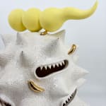 Detail of “Fat white spooter” by Kartini Thomas, showing yellow horned form atop with gold luster and sharp-toothed mouths.