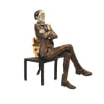 A large sculpture of a banker seated on a chair with a backrest made of stacked gold bullion. The figure, dressed in a formal suit with arms crossed, has a polished, reflective face that adds a surreal element to the piece. One chair leg is visibly bending under the weight of the gold, symbolizing the burden of wealth.