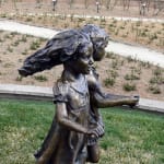 Profile view of the bronze sculpture of two young girls holding hands and skipping, capturing movement and joy, part of the Expressions of Love series.