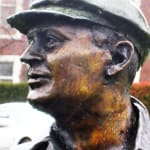 Close-up view of Bill Woodfull's bronze statue, highlighting the intricate detailing of his profile, including his cap and textured expression, which captures his thoughtful demeanor.