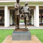 A closer look at the Shore Boys statue from a front angle, emphasizing the intricate details of the clothing and the expressions that capture the essence of mentorship and camaraderie.
