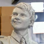 A close-up view of the clay sculpture of a young boy, part of the Shore Boys statue, showcasing his cheerful expression and neatly styled hair. The attention to detail in his features reflects his youthful energy and optimism.