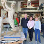 Allan Border stands beside sculptor Linda Klarfeld and another guest in her studio. The life-size clay model of his statue dominates the background, showcasing the dynamic cricketing pose and fine details before the bronze casting process.