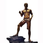 A bronze statuette of Scott, capturing his casual yet confident pose. The figure is shirtless, wearing shorts, and barefoot, standing on a rocky base. The statuette highlights Scott's athletic physique and relaxed demeanor.