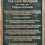 Bronze plaque dedicated to Lord Alistair McAlpine, inscribed with details about his contributions to Broome. The text highlights his work in transforming the town into a renowned tourism destination, founding the Cable Beach Club and the Pearl Coast Zoological Gardens, and restoring historical buildings. It notes his promotion of local culture, Indigenous art, and community work. The plaque concludes by recognizing him as Freeman of Broome in 2012.