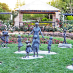 Outdoor bronze sculpture series featuring children and a grandmother interacting in various playful and loving poses at Hunter Valley Gardens